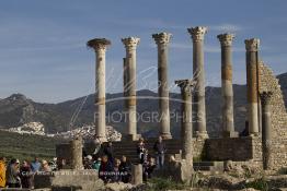 Image du Maroc Professionnelle de  Les touristes se rassemblent autour des piliers du Capitole en ruine, ancien temple de Jupiter dans la ville romaine en ruine de Volubilis l'un des sites les mieux préservés au Maroc et le plus visité. Il se situe à proximité de Moulay Idriss Zerhoun à une trentaine de km au nord-ouest de Meknès, photo prise le jeudi 8 Mars 2012. Volubilis ville antique berbère Walili (Lauriers rose) qui date du 3e siècle avant J.-C. capitale du royaume de Maurétanie fondé comme seconde capital sous le règne de Juba II. (Photo / Abdeljalil Bounhar)
 